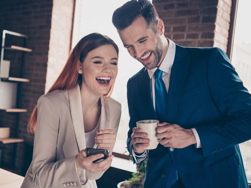 Lustige Bürosprüche: Kollegen lachen miteinander über lustige Sprüche für die Arbeit