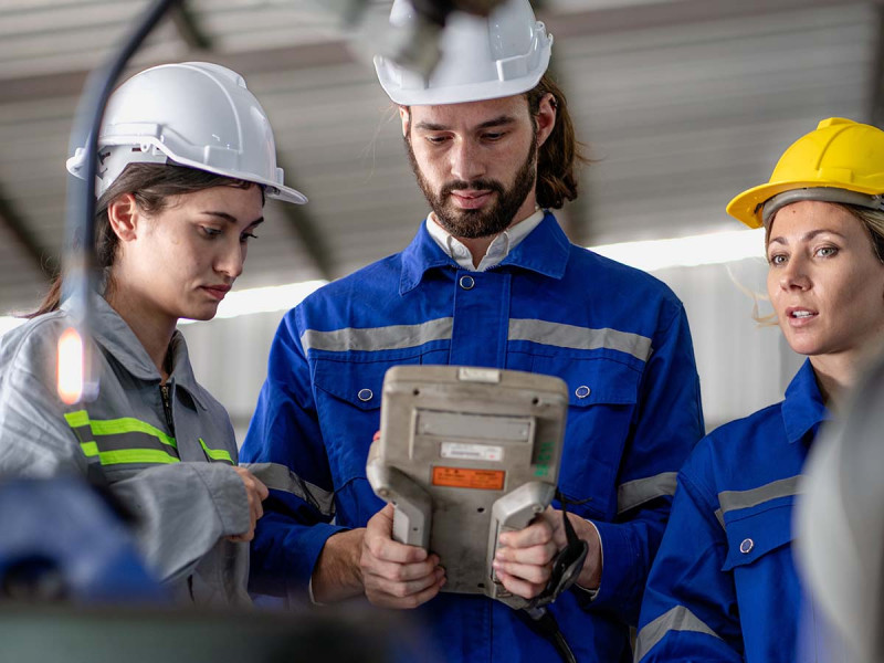 Industrietechniker überprüft den Betrieb eines Schweißroboters in einer modernen Automatisierungsfabrik mit Hilfe einer Fernsteuerung.