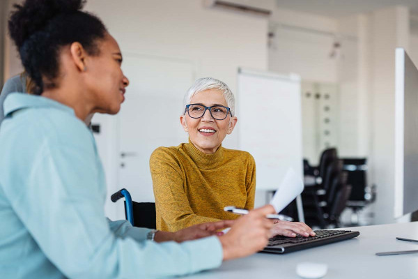 Zwei Mitarbeiterinnen in der Personalabteilung besprechen digitale HR-Prozesse am Computer im modernen Büro