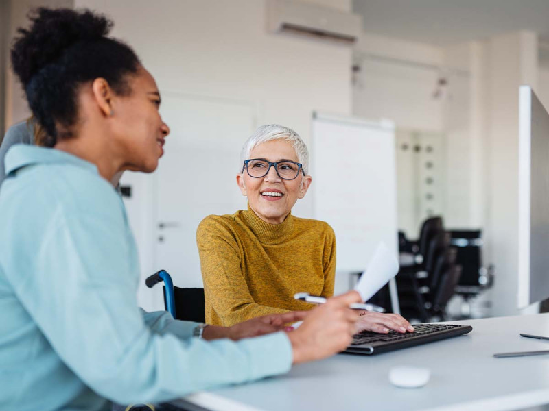 Zwei Mitarbeiterinnen in der Personalabteilung besprechen digitale HR-Prozesse am Computer im modernen Büro
