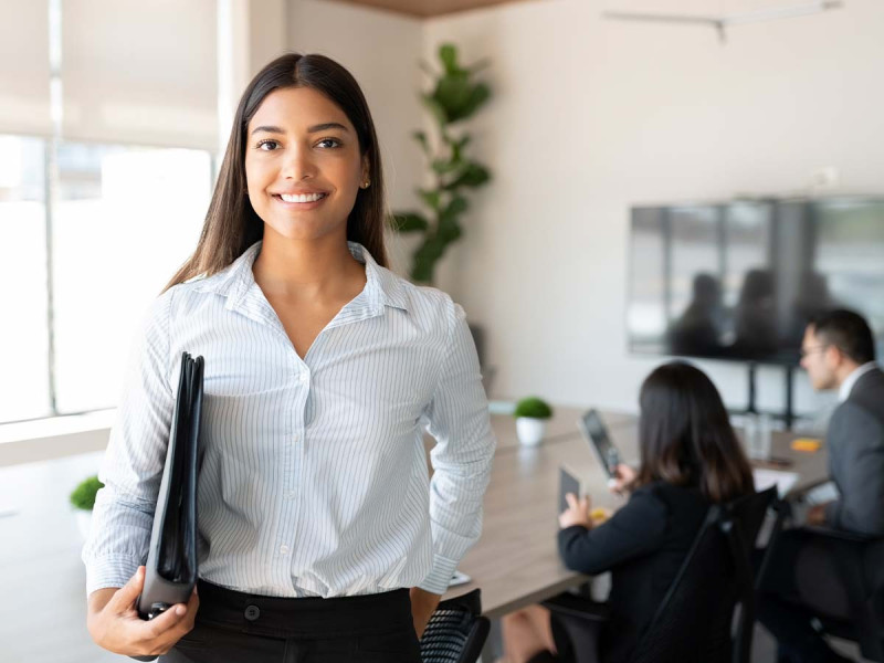 Führungskraft werden ohne Erfahrung: Young Professional in einem Geschäftstermin - lächelnd in die Kamera