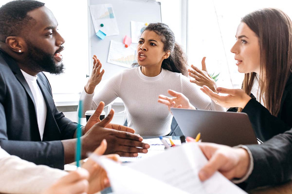 Schlechte Stimmung im Team: drei Kollegen die sich untereinander während der Arbeit streiten