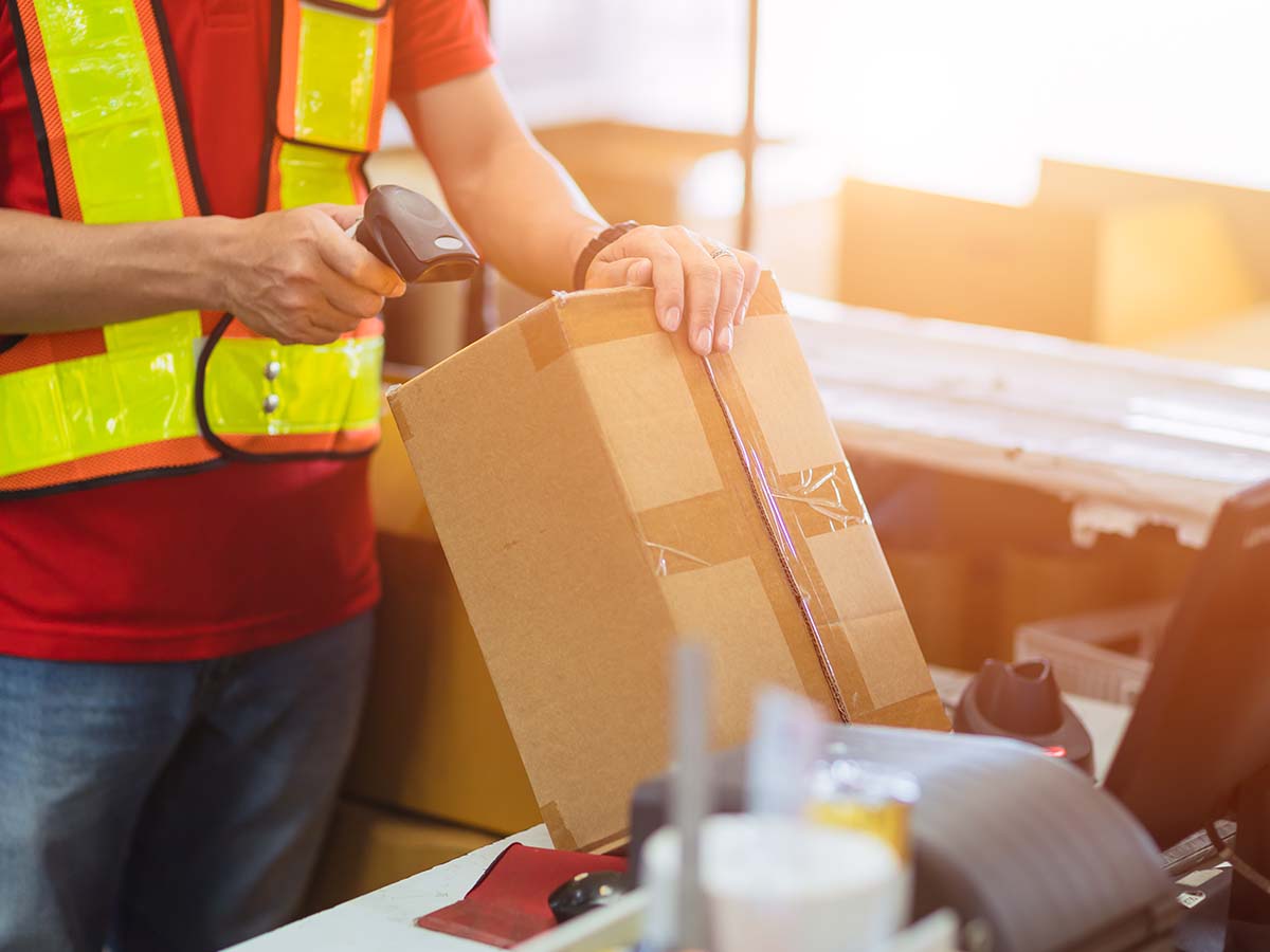 Mitarbeiter, der ein Paket scannt und sortiert