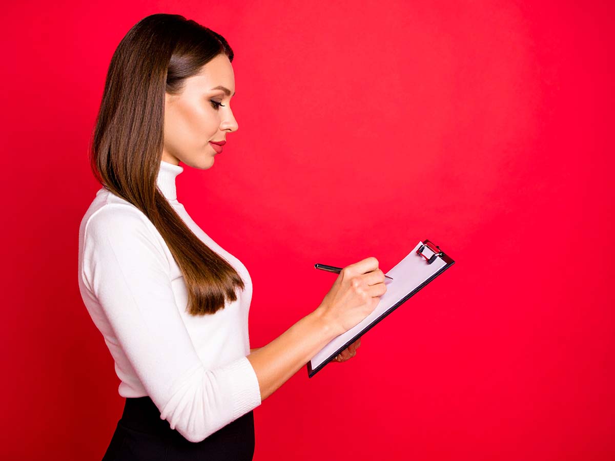 Junge Frau mit Klemmbrett notiert Strategien zur Selbstreflexion und Stressprävention – praktische Tipps für gesundes Work-Life-Blending im Berufsalltag.
